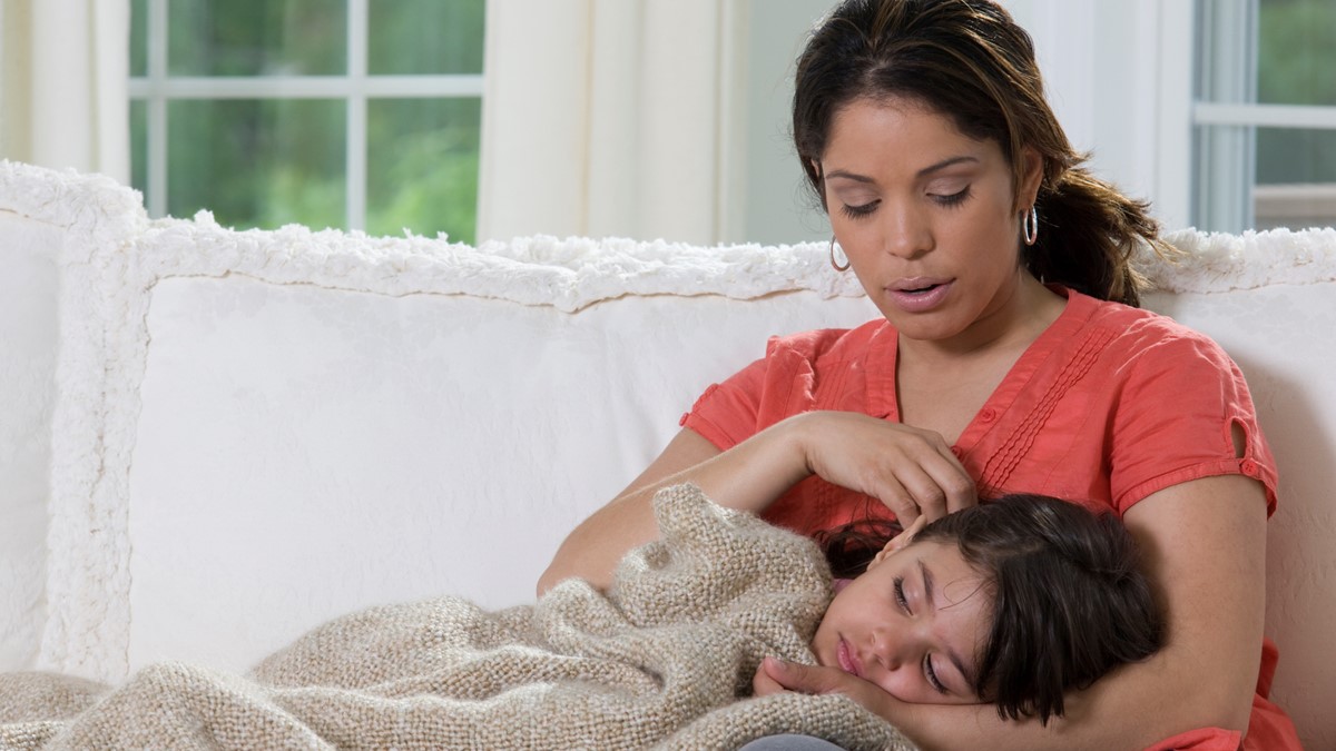 A woman holds a young child who is not feeling well.