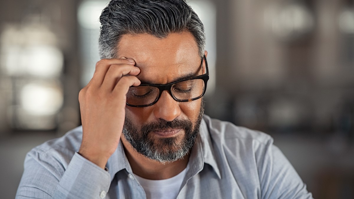 -- title missing -- Man wearing glasses touching head as if he has a headache.