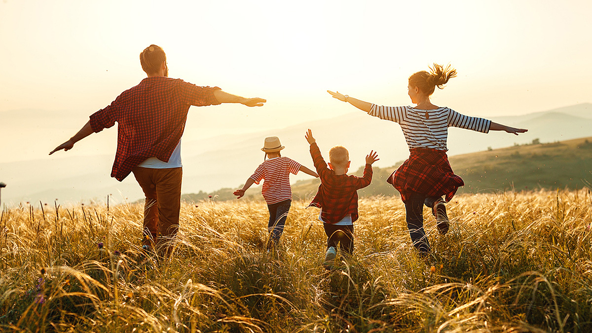 Family Running at Sunset Young family running in a field, arms out, at sunset.
