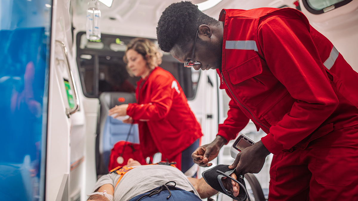 Community Paramedicine Two EMS technicians working on a patient laying on a gurney in an ambulance