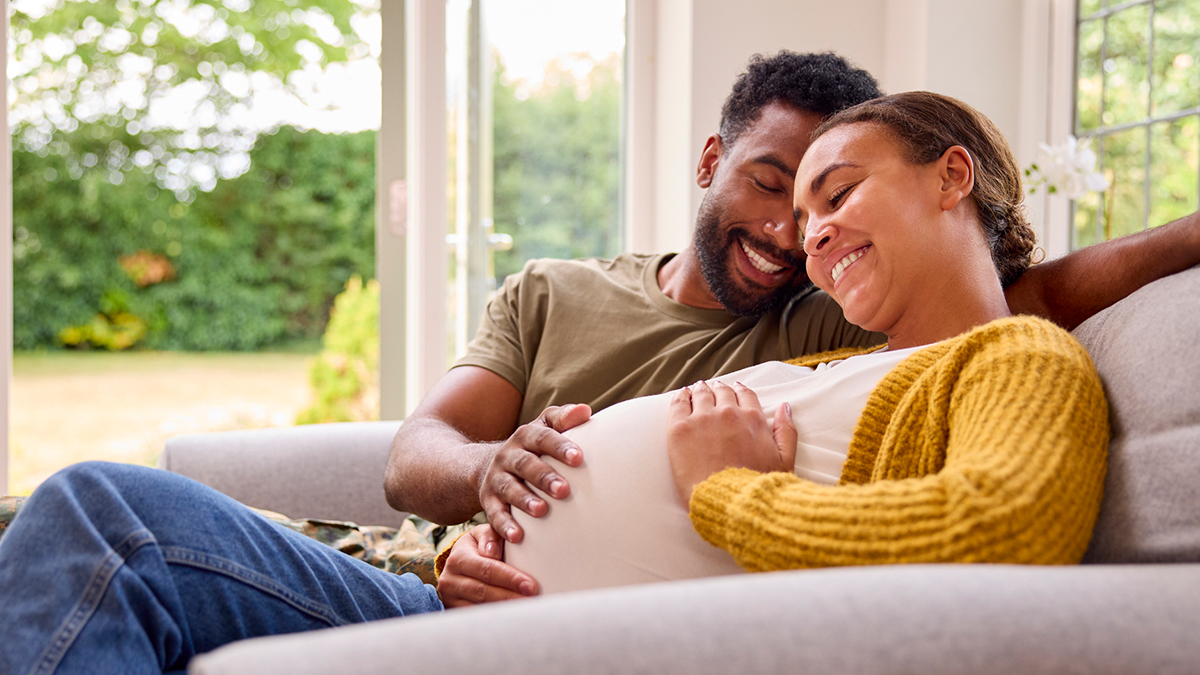 A pregnant woman a pregnant woman sitting on a couch with her partner