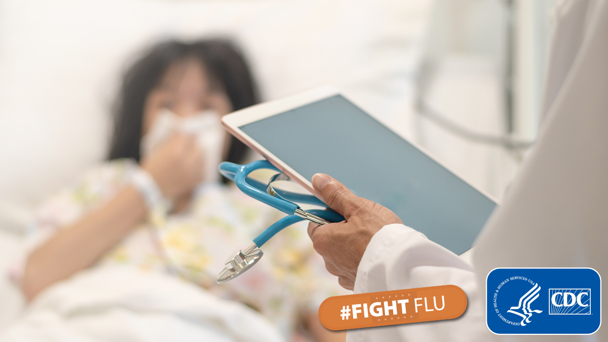 A doctor holding a tablet and a patient in a hospital bed. A doctor holding a tablet and a patient in a hospital bed.