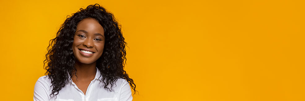 Flu banner Woman with curly hair smiling in front of a yellow background.