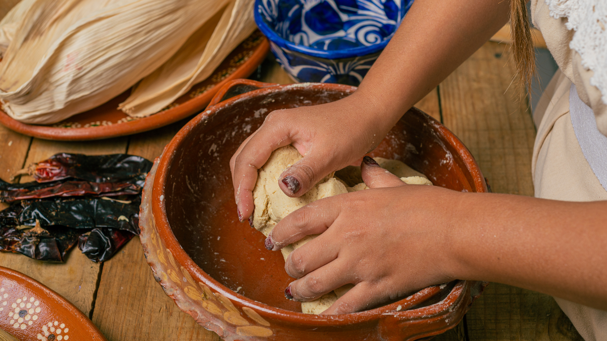— title missing — A person working corn masa dough to make tortillas on a wooden table.