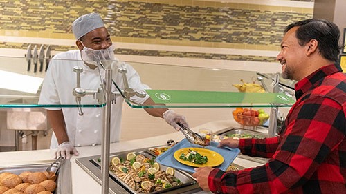 — title missing — Food service worker serving man in cafeteria line.
