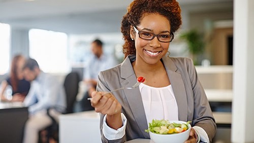 Expand woman in cafeteria Woman eating salad in cafeteria.
