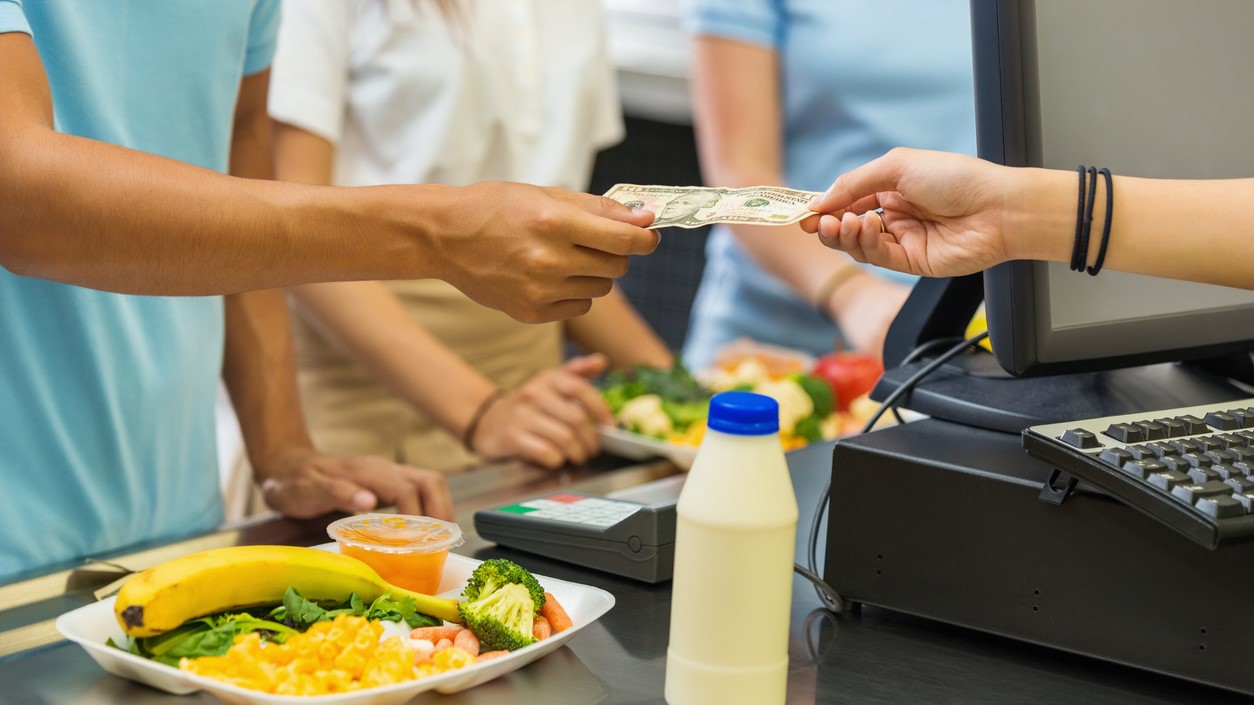 — title missing — Person paying for meal with cash in a cafeteria.