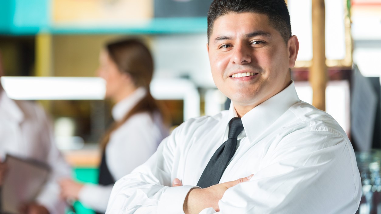 — title missing — Food service vendor standing with arms folded and smiling at camera.