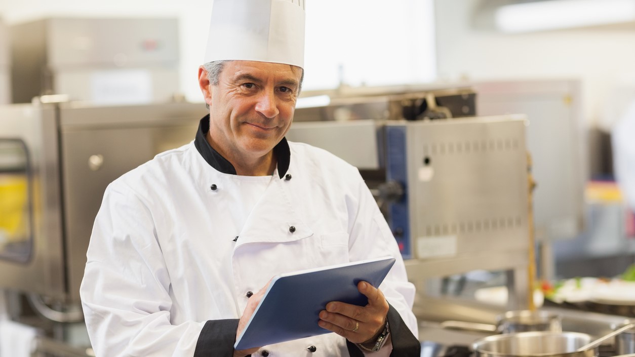 — title missing — Chef with clipboard in commercial kitchen.