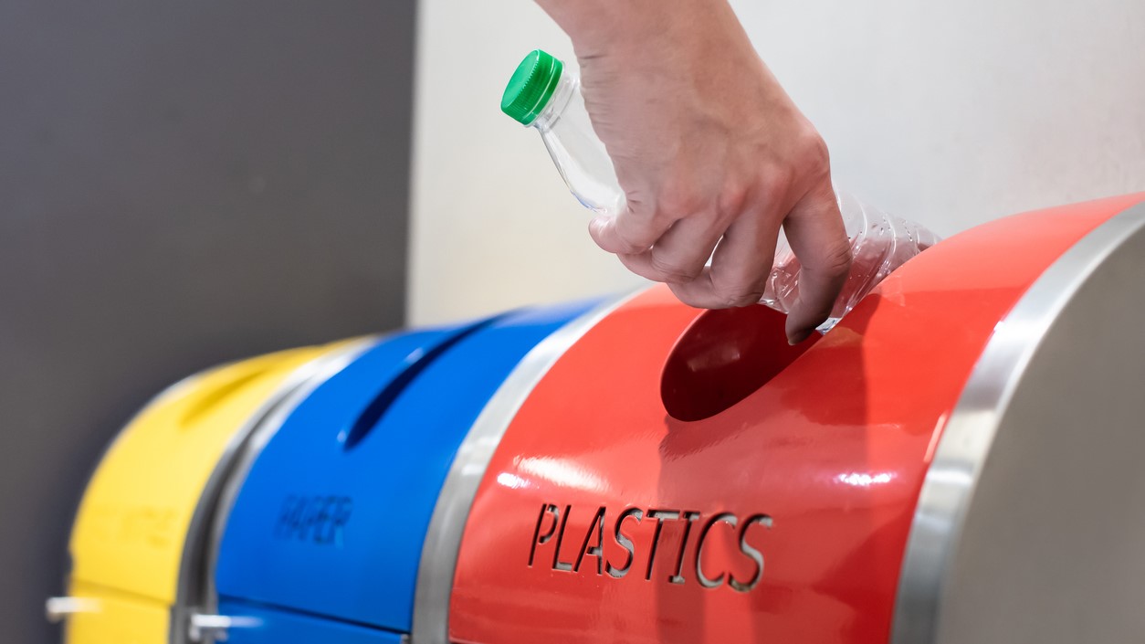 — title missing — Person putting plastic bottle in recycling bin.