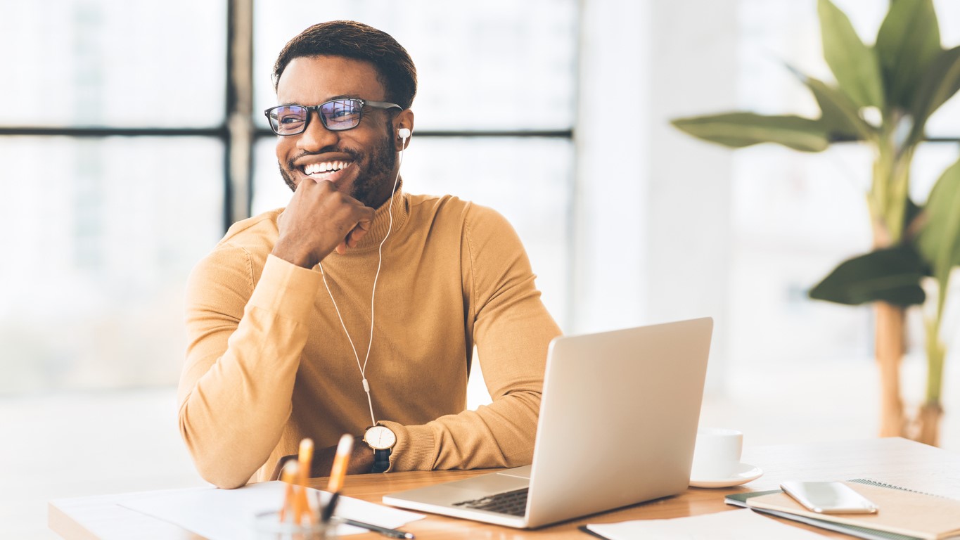 — title missing — Smiling man in office with laptop computer.