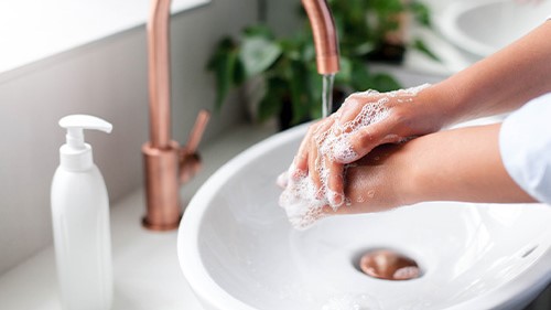 Handwashing at sink Person rinsing soap bubbles off their hands using a home sink