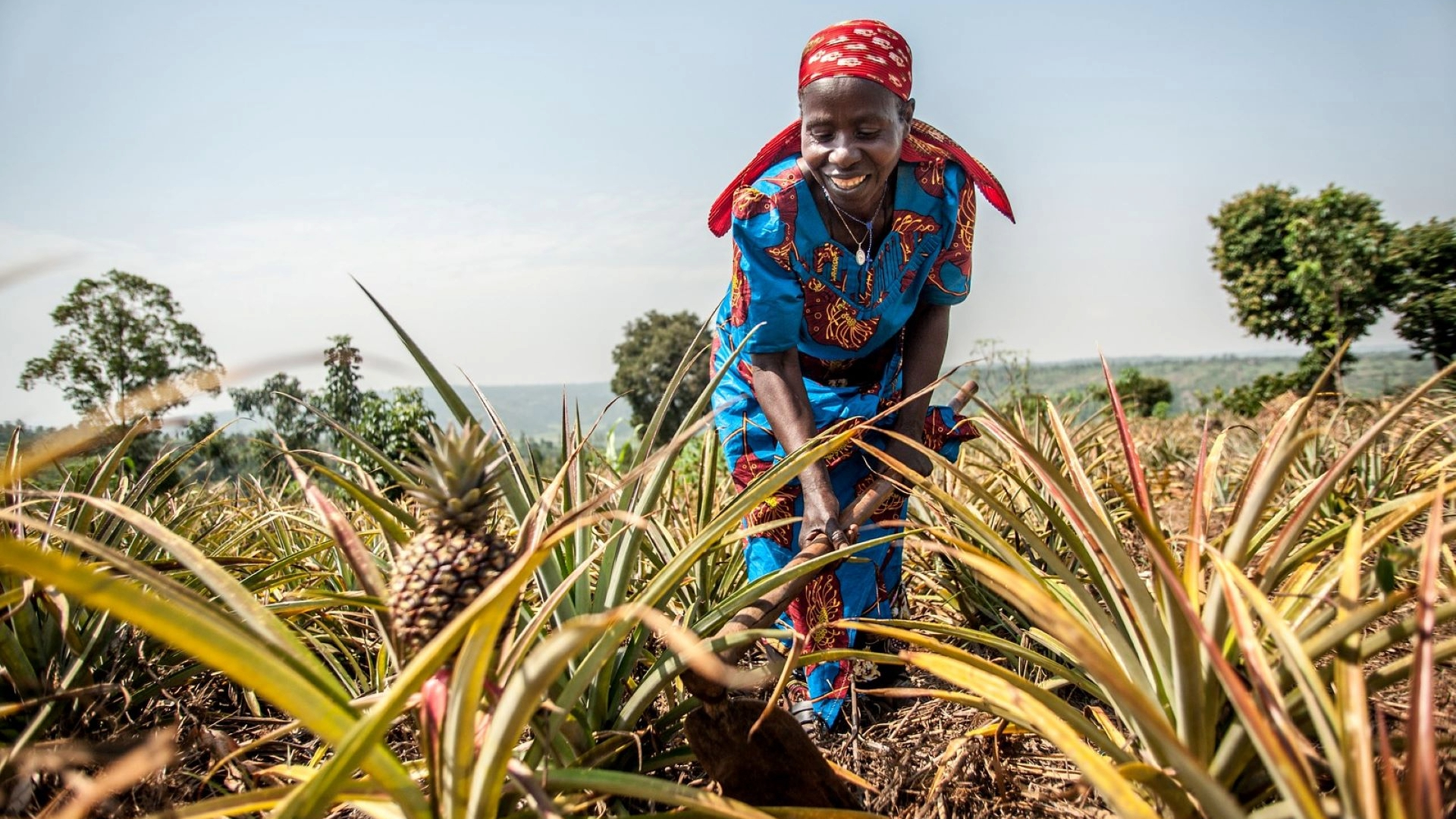 Approach-3 African lady dressed in traditional clothing in a field.