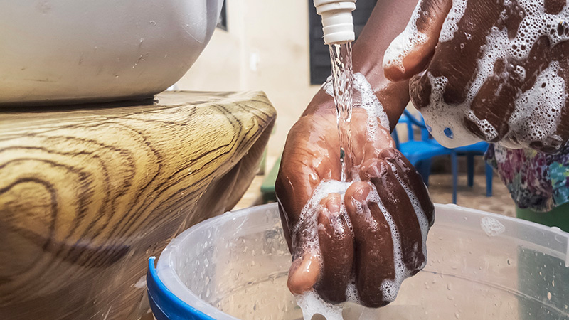 Soapy hands Closeup of a woman’s soapy hands being rinsed under a large container of water