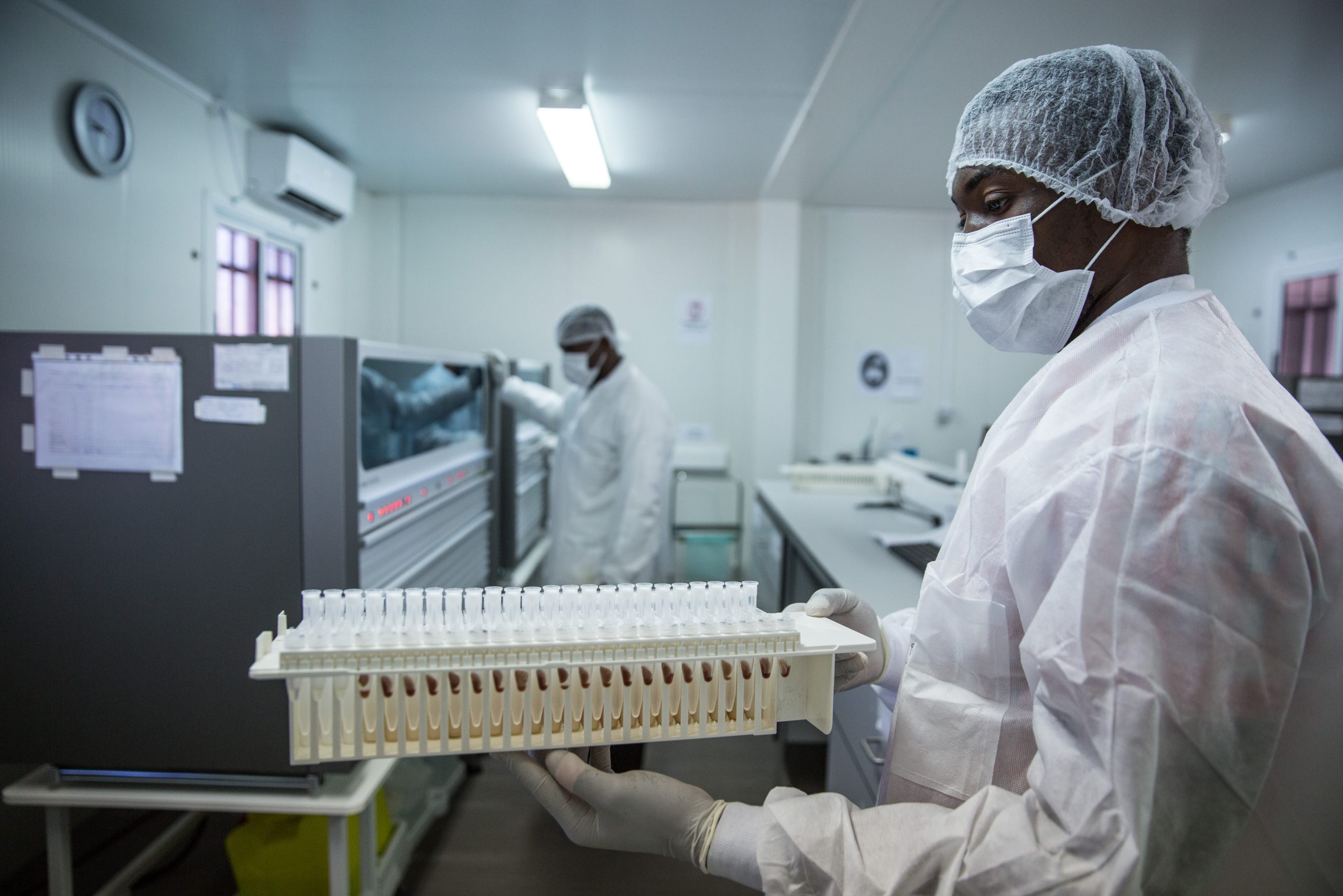 WFED Lab Worker A man wearing white lab gear, blue gloves, a mask, and hair protection stands in a laboratory.