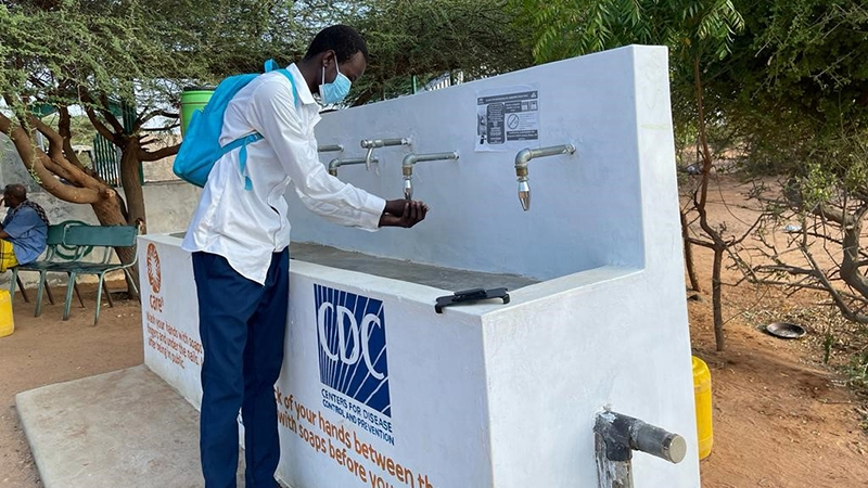 handwashing-station-dadaab3_16x9 A person washes their hands at an outdoor handwashing station.