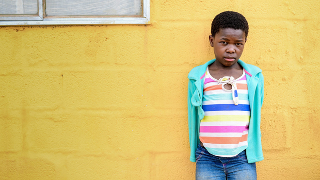 11-year-old Gugu alive and healthy standing in front of a yellow wall