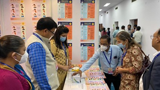 Success Story_2024_IndiaIPC Individuals stand around a table reviewing TB factsheets.