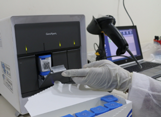 2024_SuccessStory_WTBD A microbiologist inserts sample into an Xpert machine to diagnose DR-TB.