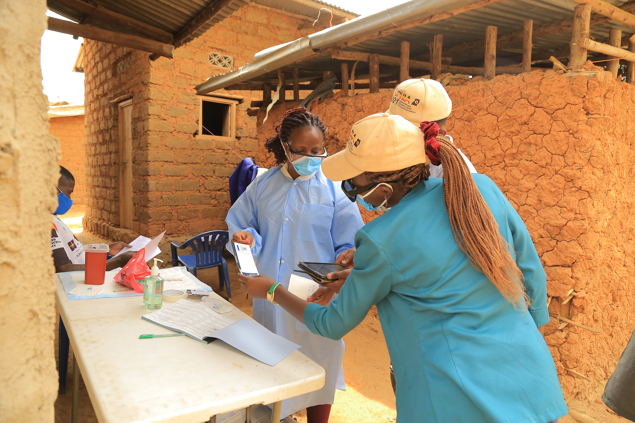 Uganda RUPHIA Three public health workers reviewing a document in a Uganda community.
