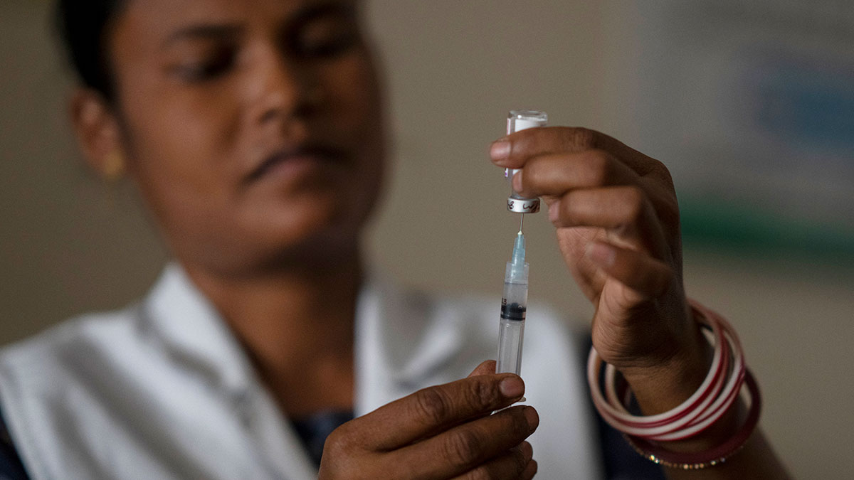 Loading a vaccination syringe in India A health worker loads a syringe with vaccine