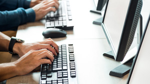 GrantSolutions Training Monitors and keyboards side by side with hands typing on the keyboards.