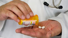Antibiotics A healthcare provider holds a pill bottle and two white pills.