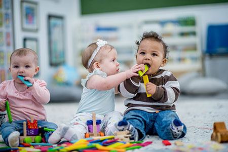 babies-playing-blocks Three babies playing with blocks and putting toys in their mouths.
