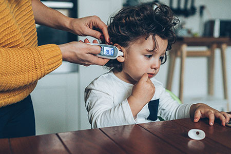 mother-toddler-thermometer Una madre le toma la temperatura a su hija con un termómetro digital.