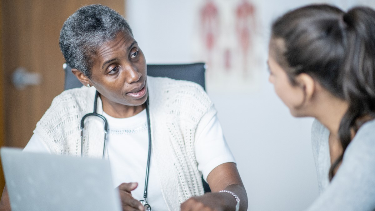 Clinician and patient A healthcare provide talking to a patient in a doctor's office