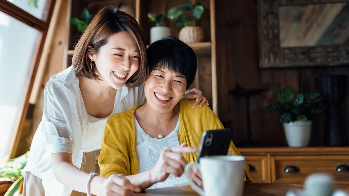 Happy Asian Mother and Daughter A mother and daughter of Asian descent smile while looking at a phone.