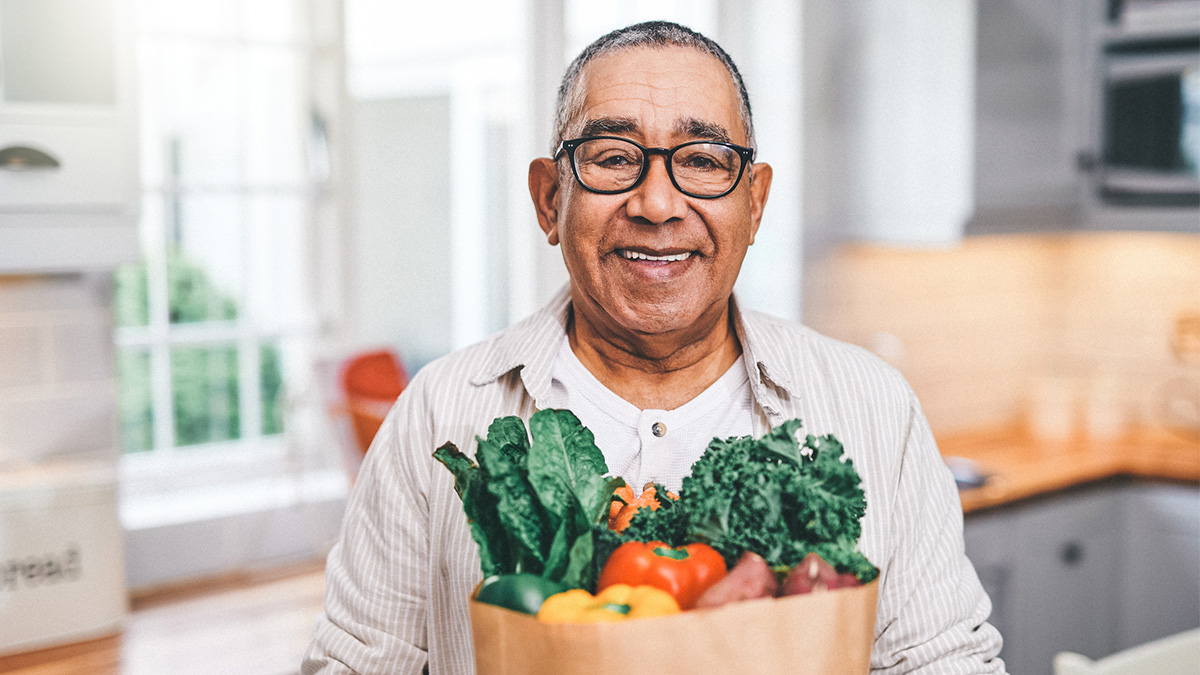 Healthy Hispanic Man An older Hispanic man smiles while holding a bag of groceries.