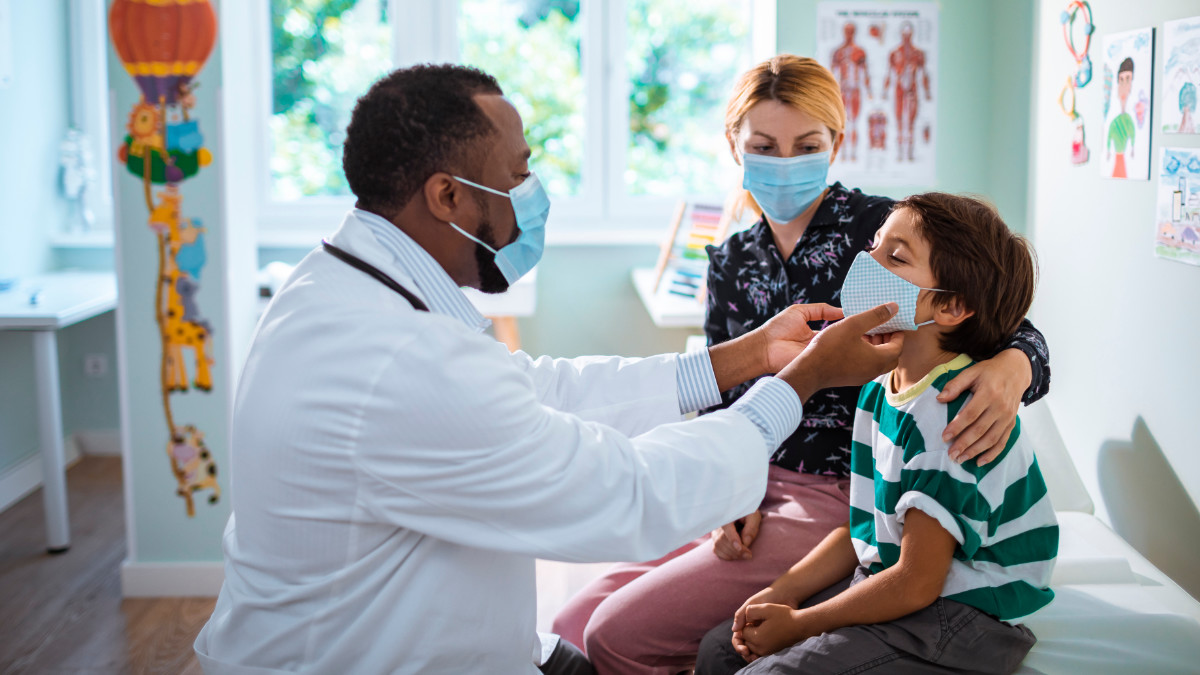 — title missing — Pediatrician treats child patient while the patient's mother observes.