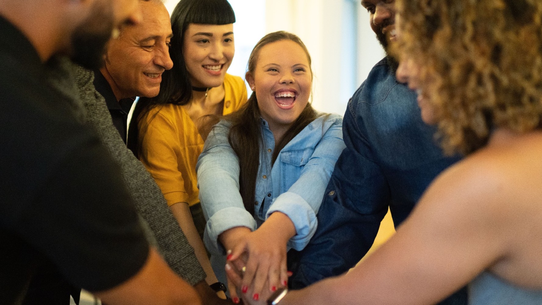 he-action Group of diverse people smiling and reaching their arms together in a circle between them.