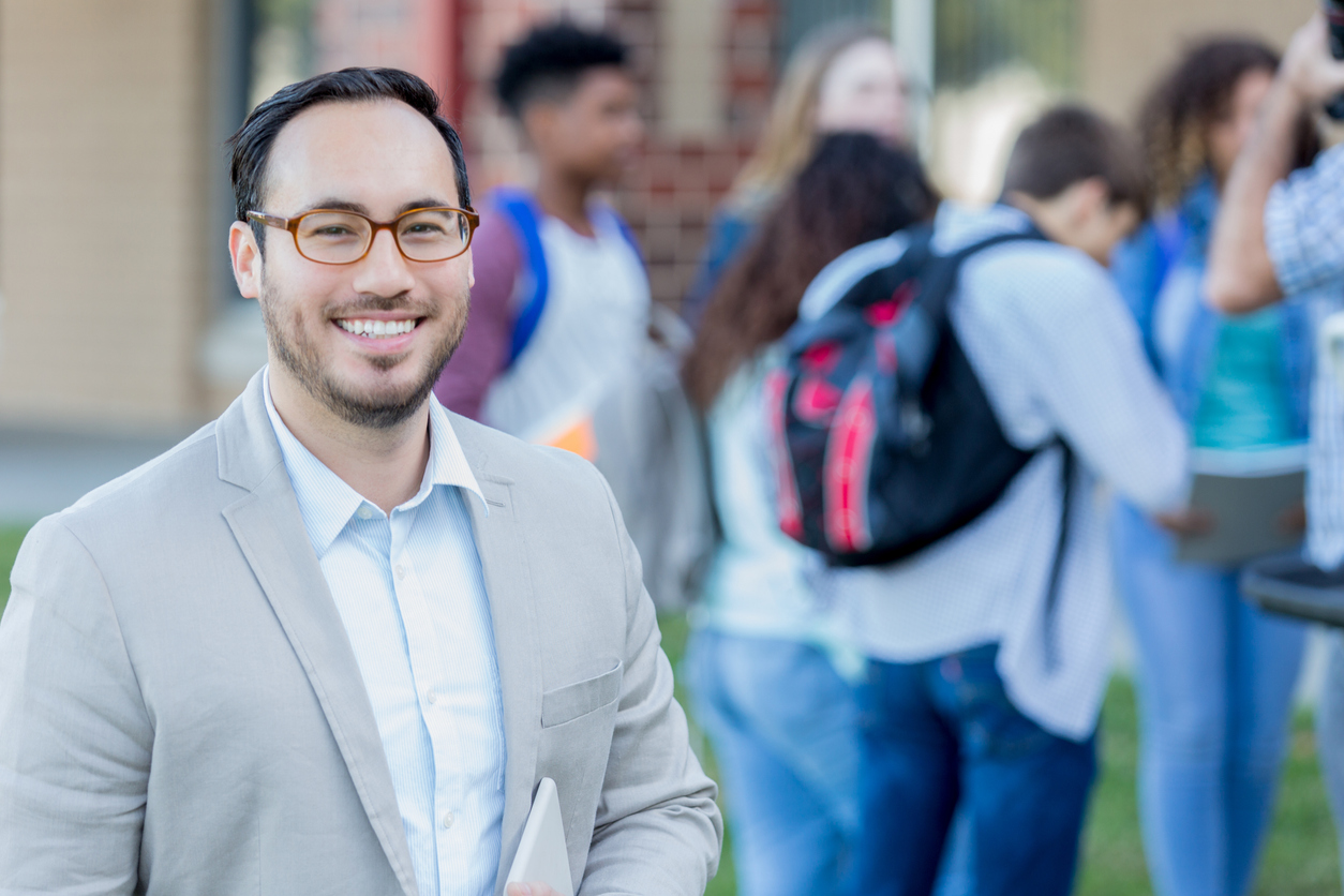 istockphoto-1034421614-1024x1024 Confident teacher standing outside of school.