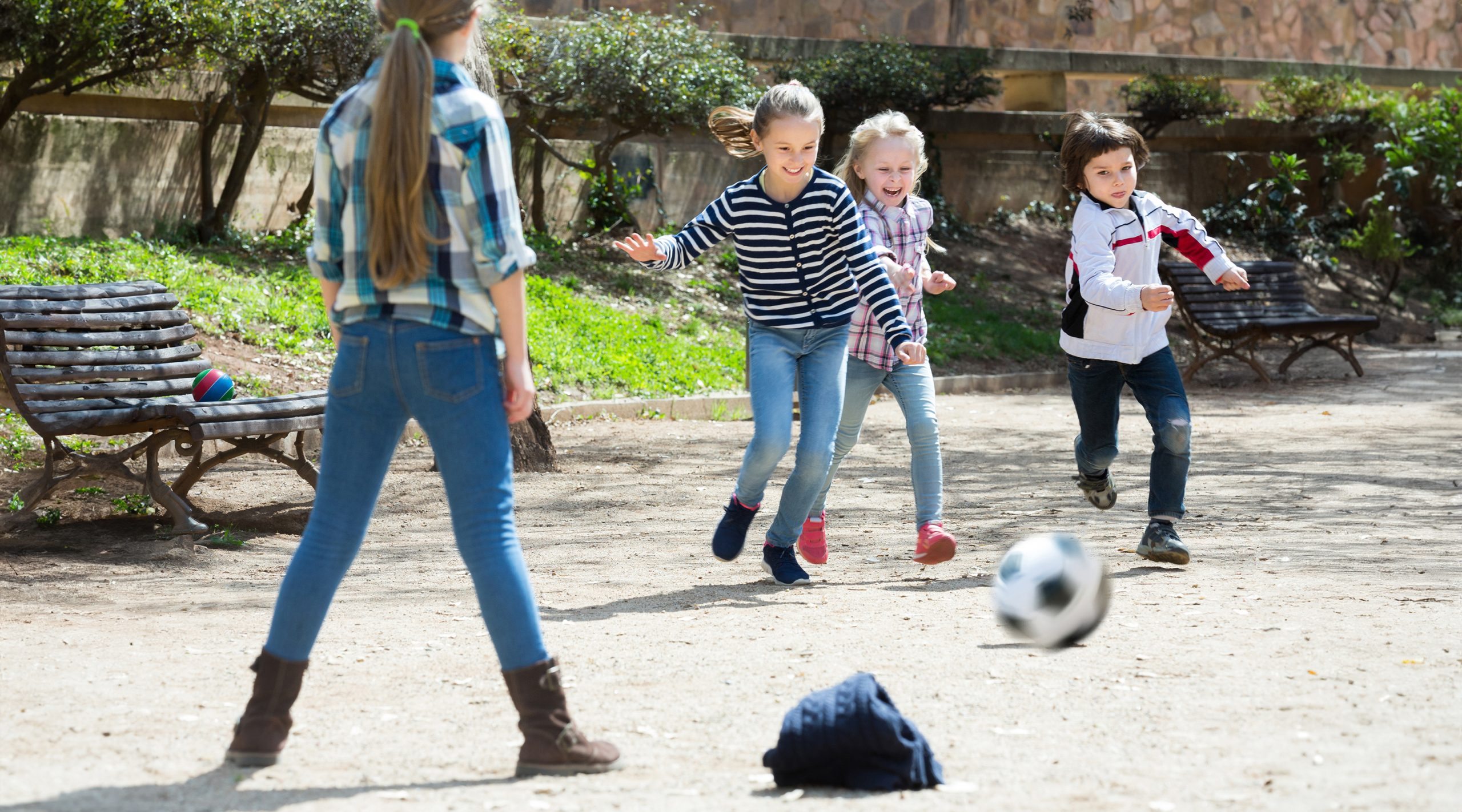 Young kids playing street football outdoors Young children kicking a soccer ball.