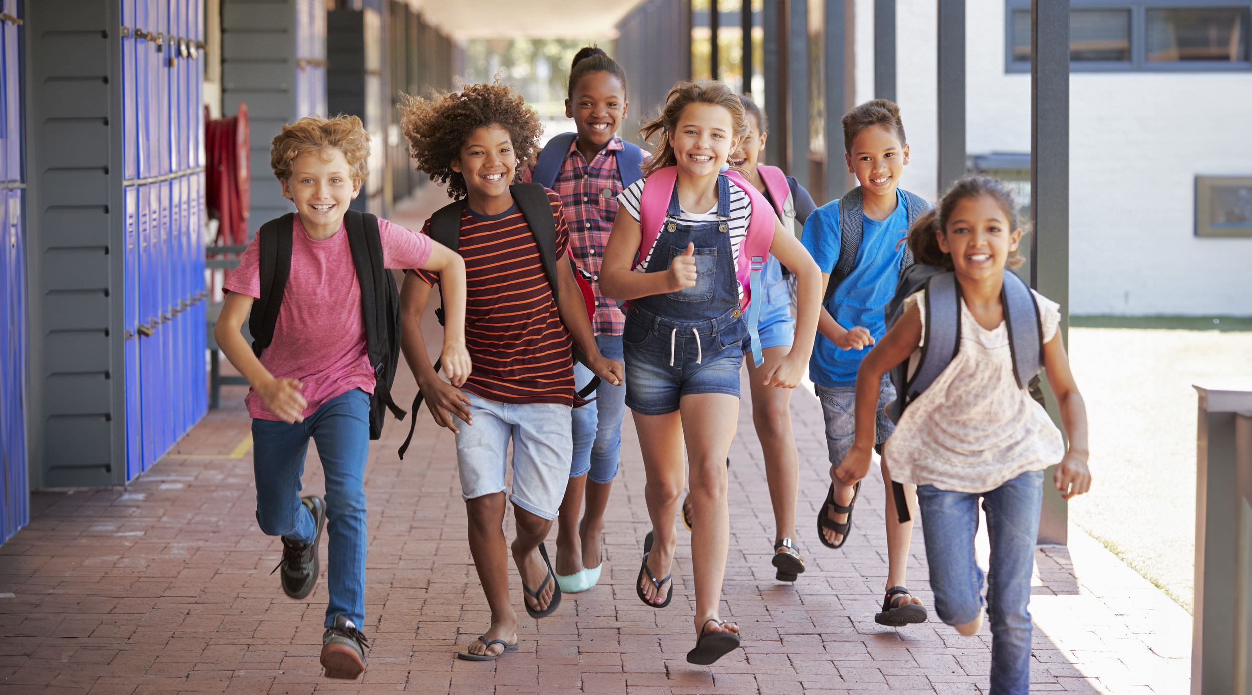 School kids running in elementary school hallway, front view Children running outside of the school.