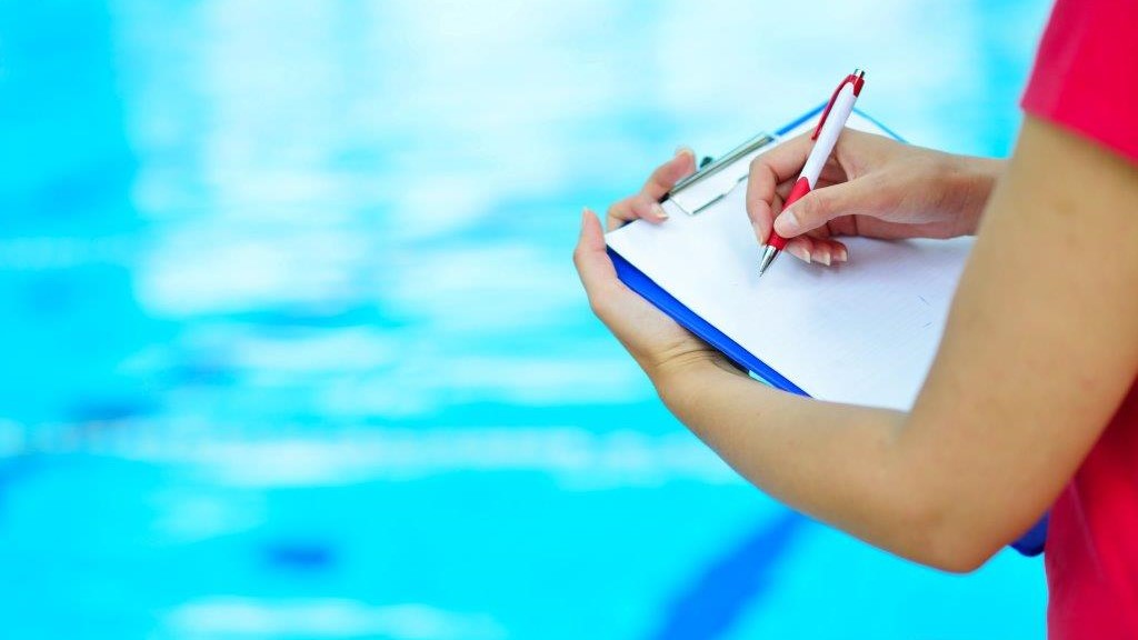 Inspection Form Resources Photo of a woman with a clipboard standing in front of a pool.