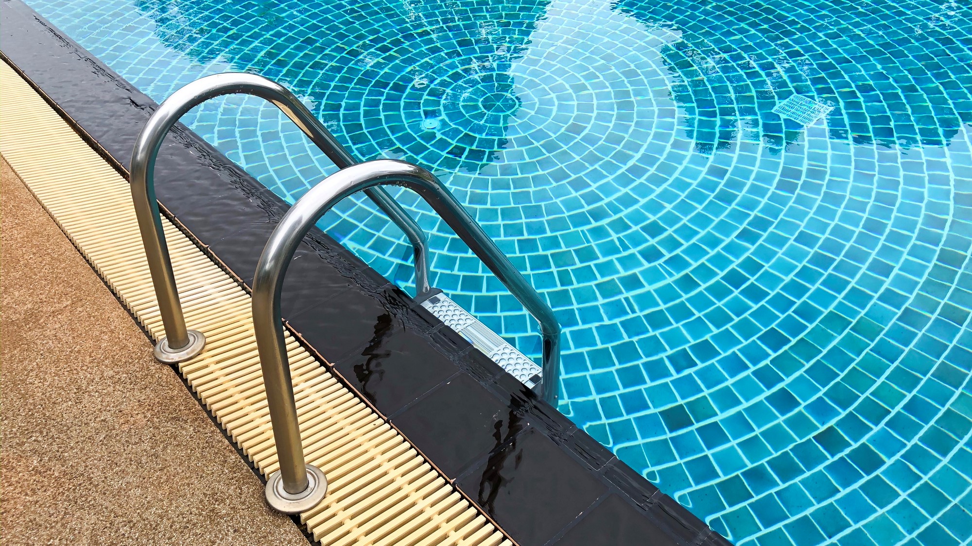 Primer plano de una escalera que lleva a la parte profunda de una piscina.