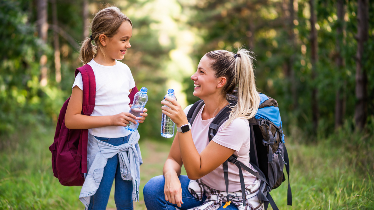 Mother and daughter drinking water while hiking Mother and daughter drinking water while hiking