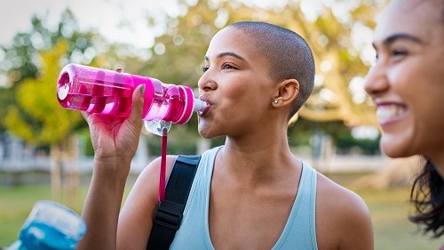 — title missing — Woman drinking water from a refillable bottle.