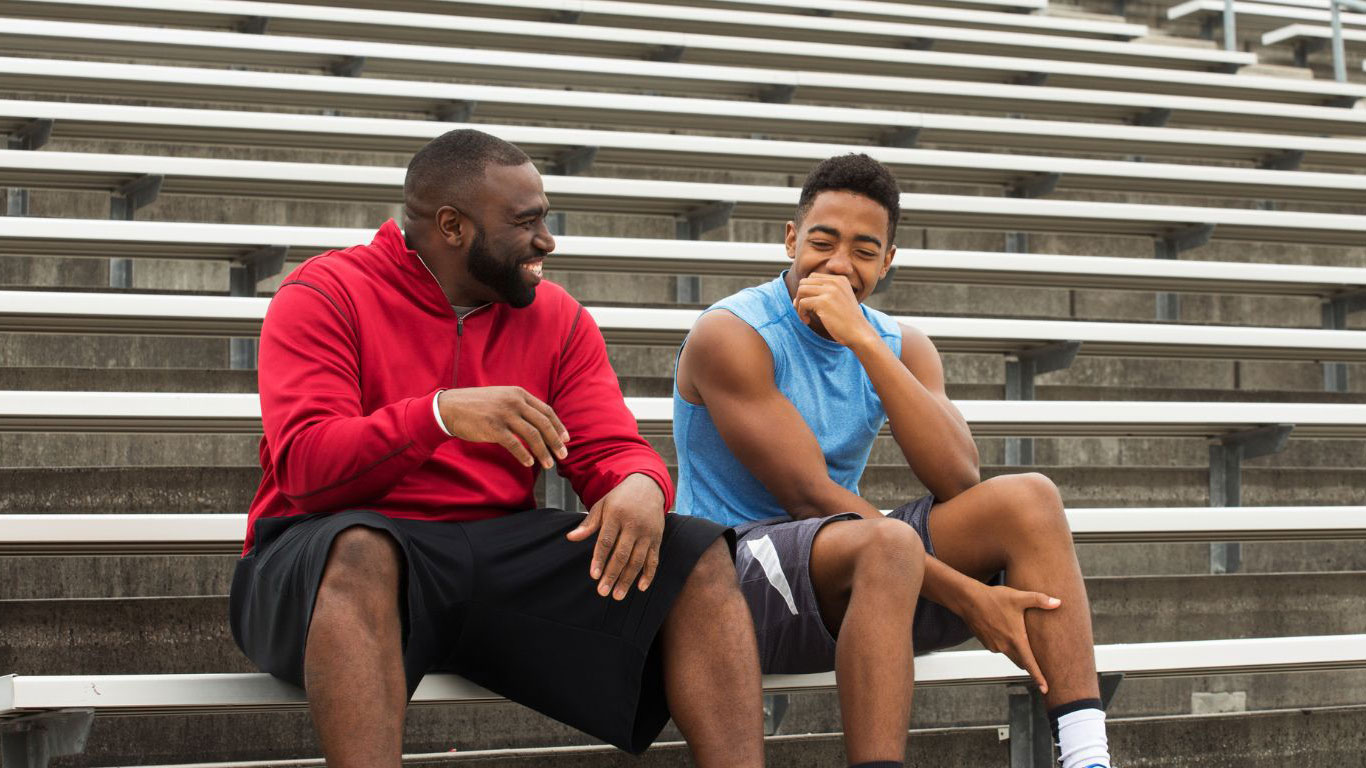 Talking with your teen A father talking to teenage son at the stadium.