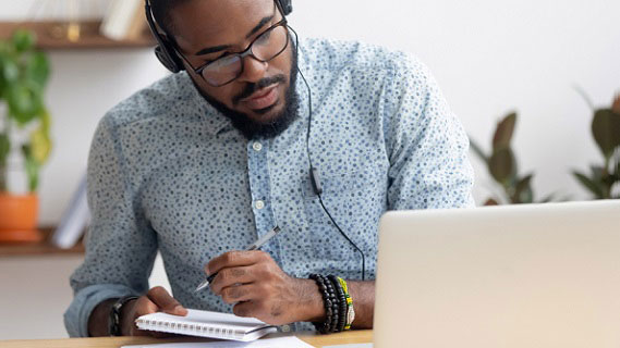 A male educator looking for funding information from a laptop.