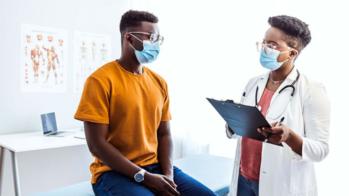 Doctor talking with male patient. Both wearing masks. Doctor talking with male patient. Both wearing masks.
