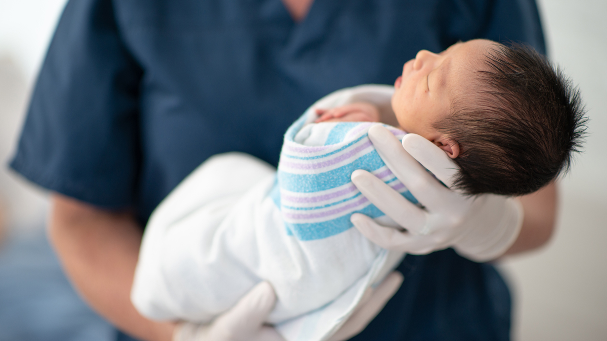 Hepatitis B Prenatal Testing Administration A healthcare professional holding a newborn baby wrapped in a blanket