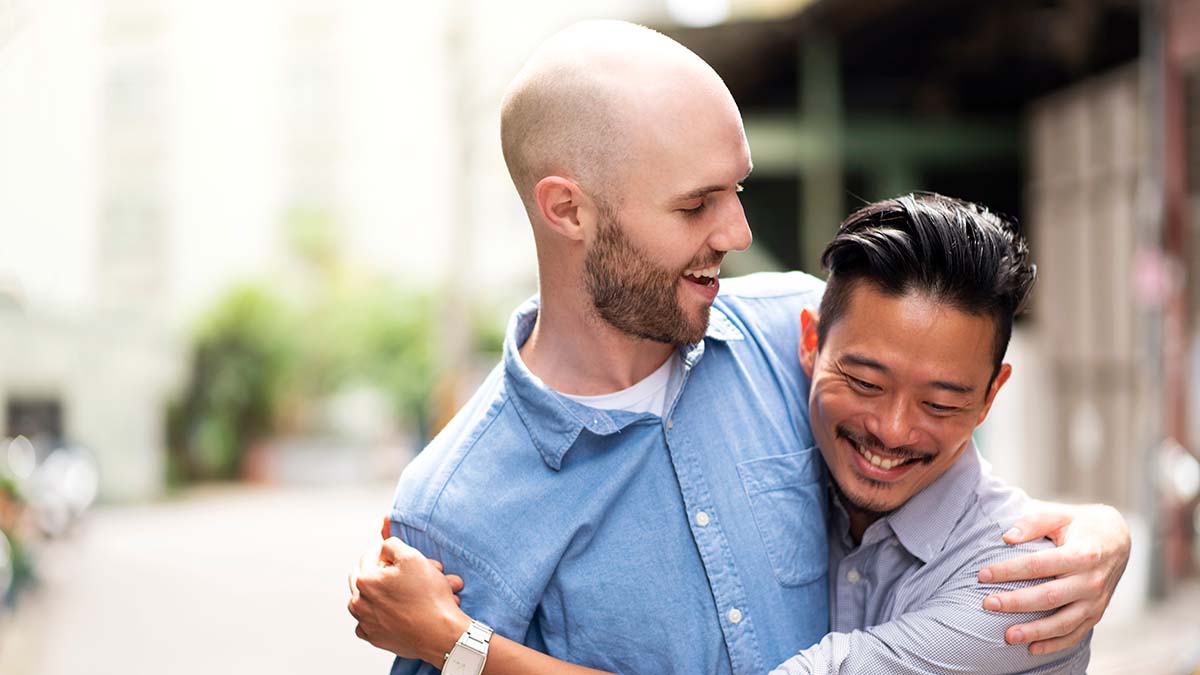 Vaccination Against Hepatitis A and B for Gay and Bisexual Men Two gay men vaccinated against hepatitis a and hepatitis b hugging walking down the street