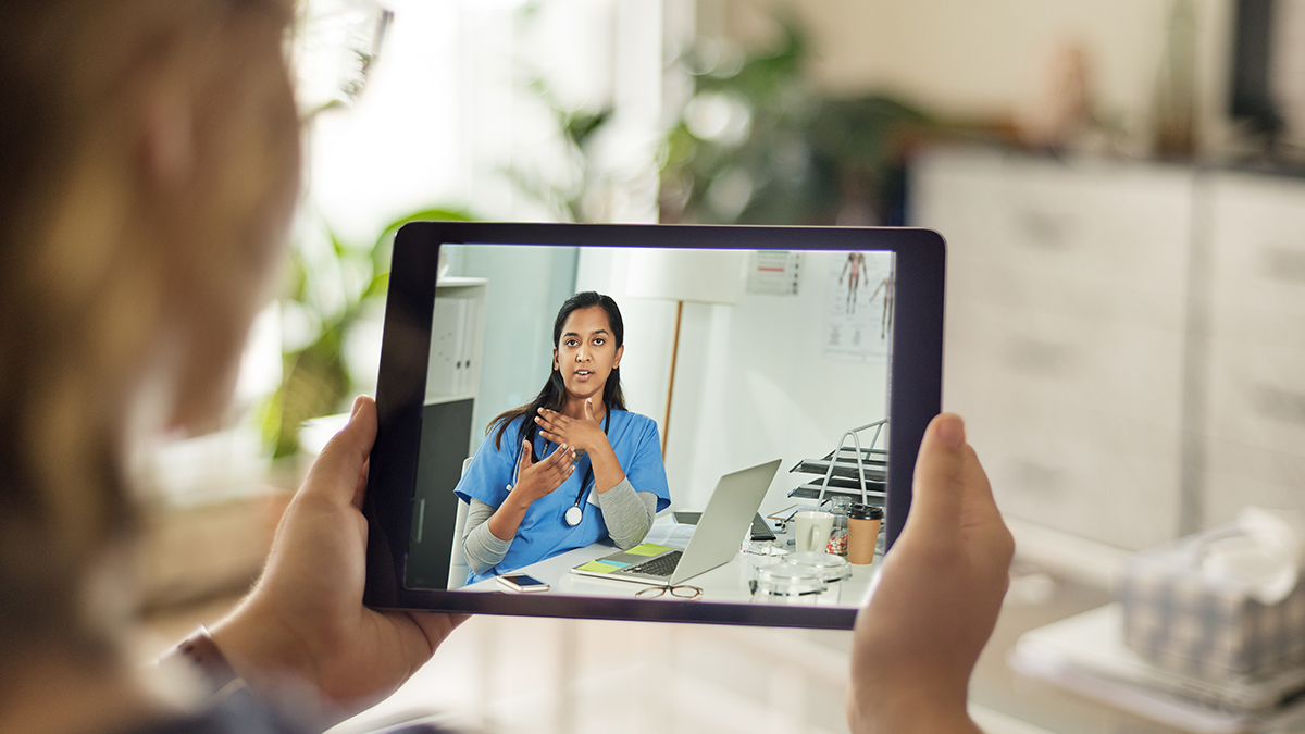 — title missing — Person having a telehealth visit with a medical professional on their tablet.