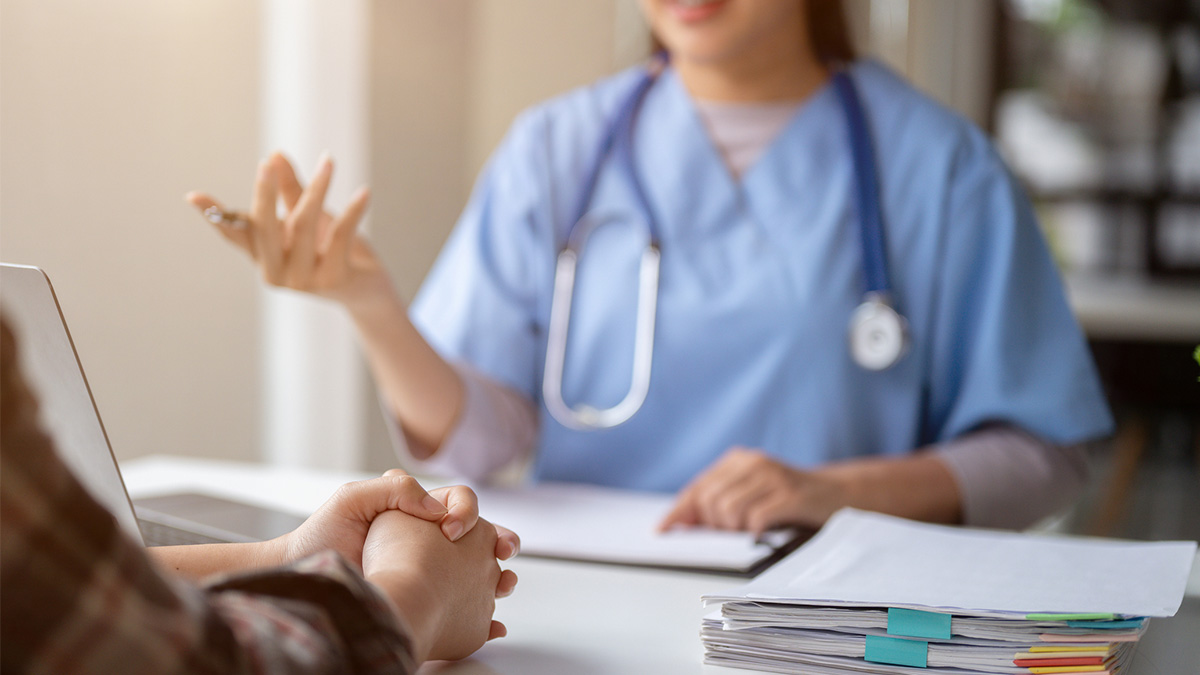 Doctor advises a serious patient. A doctor gestures while providing a medical consultation to a patient.
