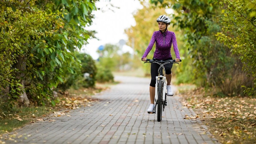— title missing — Woman riding bike on brick path.