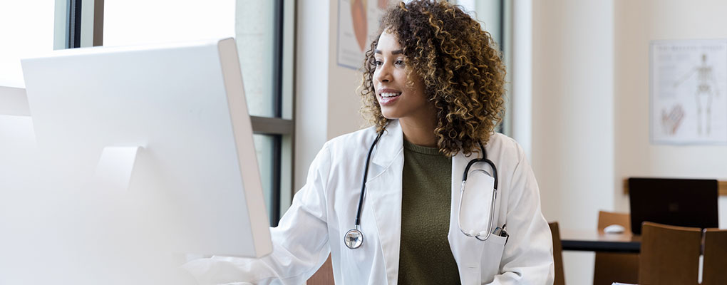 doctor-desktop Adult female doctor reviews patient records on desktop PC.